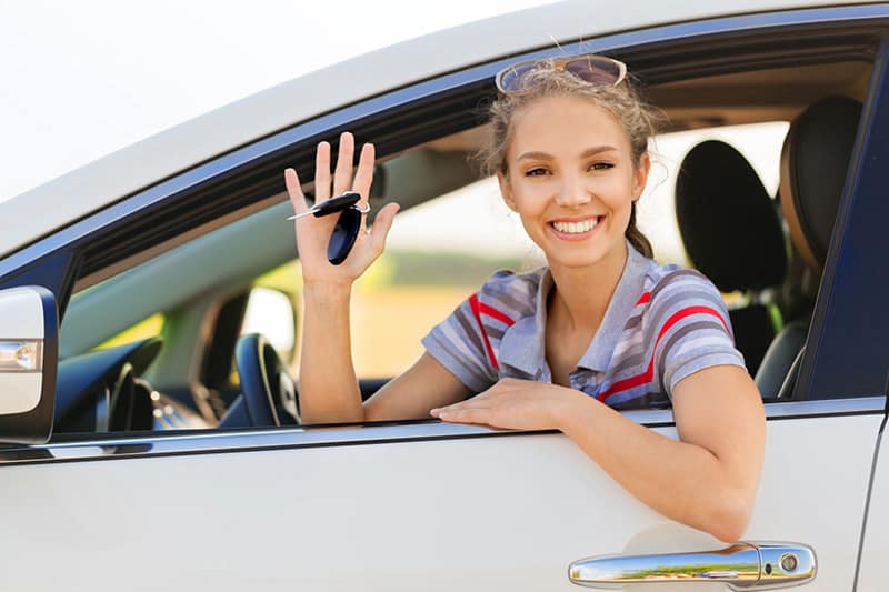 A woman sitting in the drivers seat of her car.