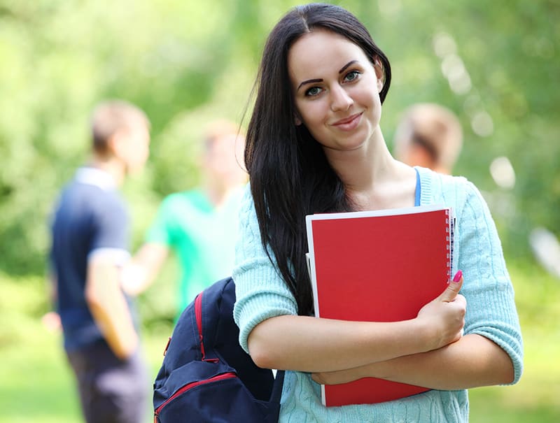 A woman holding a red book while standing in front of other people.