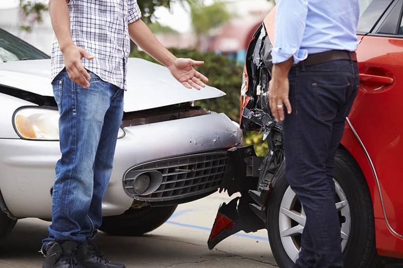 A man is standing next to an accident car