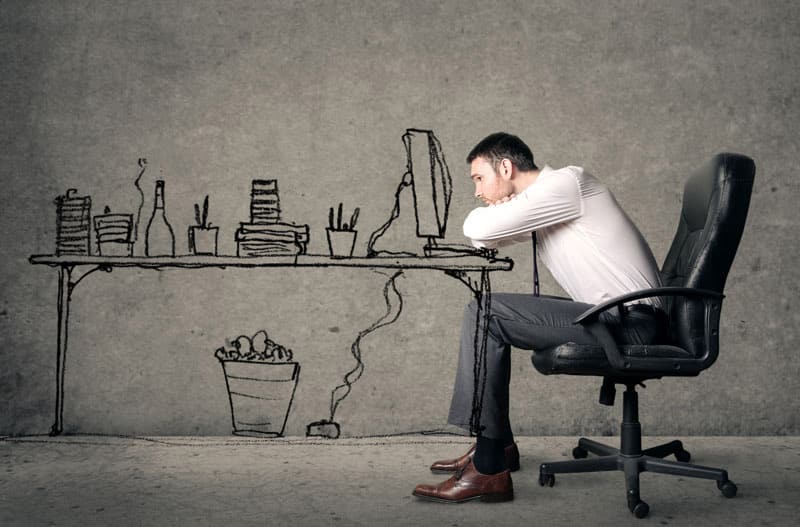 A man sitting at his desk with his head on the table.