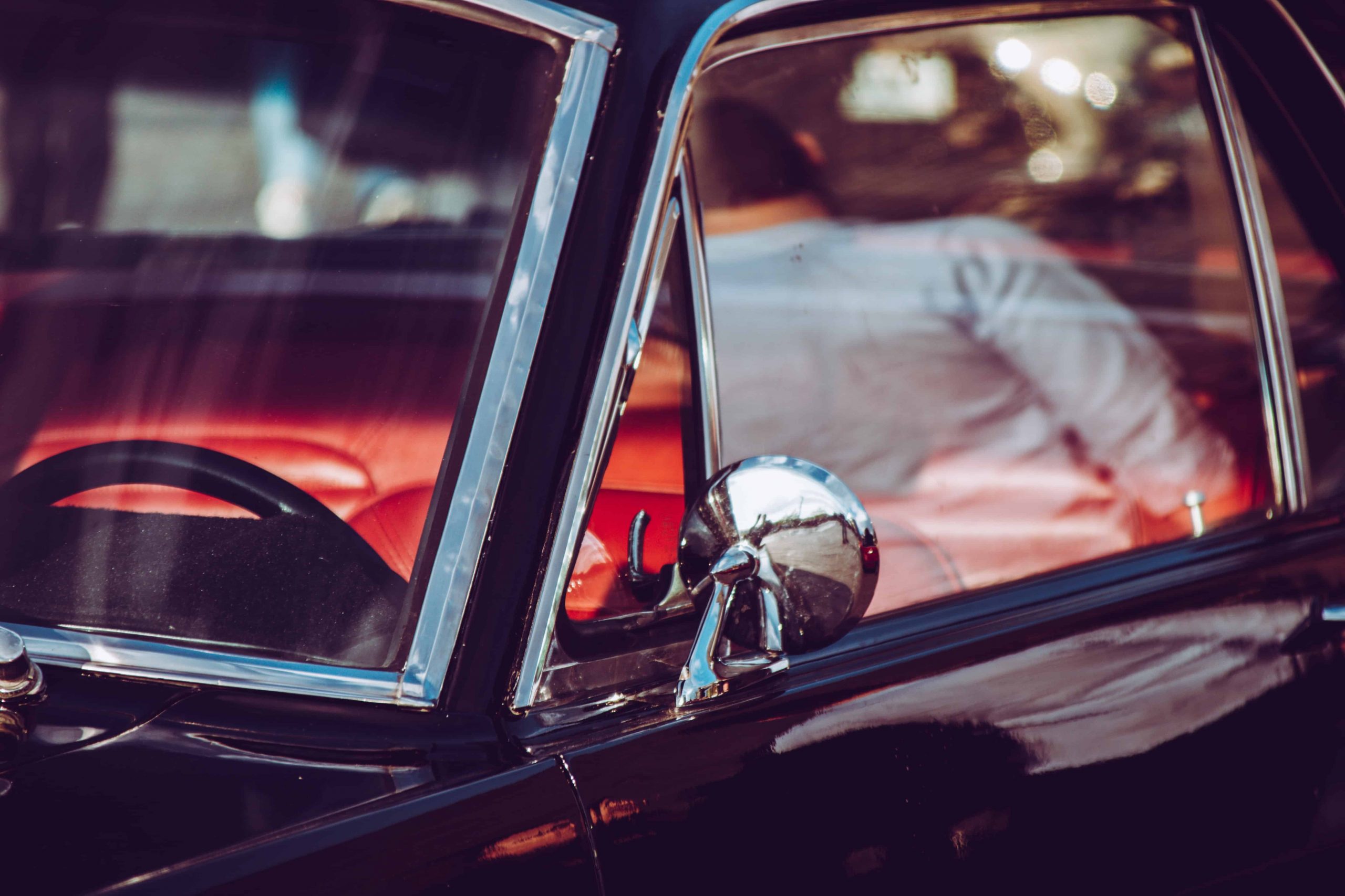 A car with the door open and side mirror reflected in it.