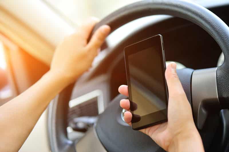 A person holding their cell phone while driving.