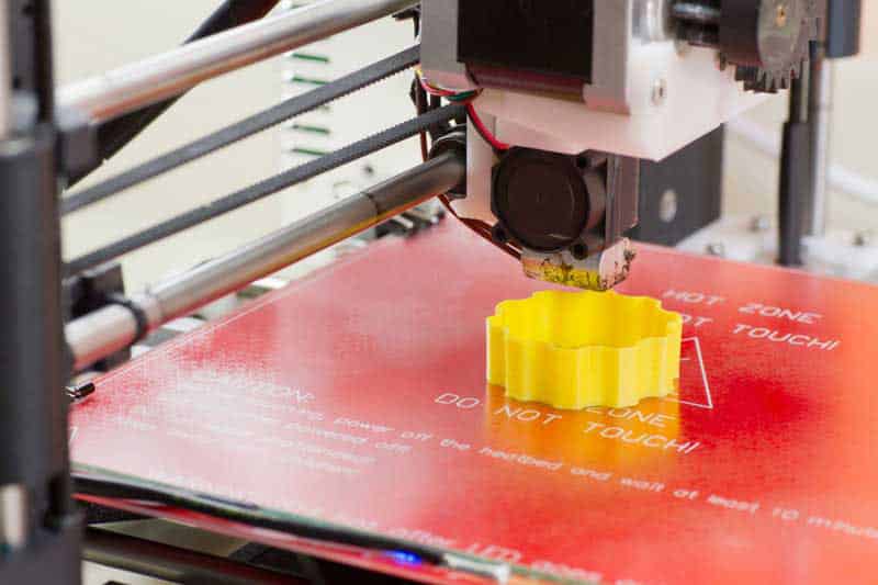 A yellow object is being printed on the 3 d printer.