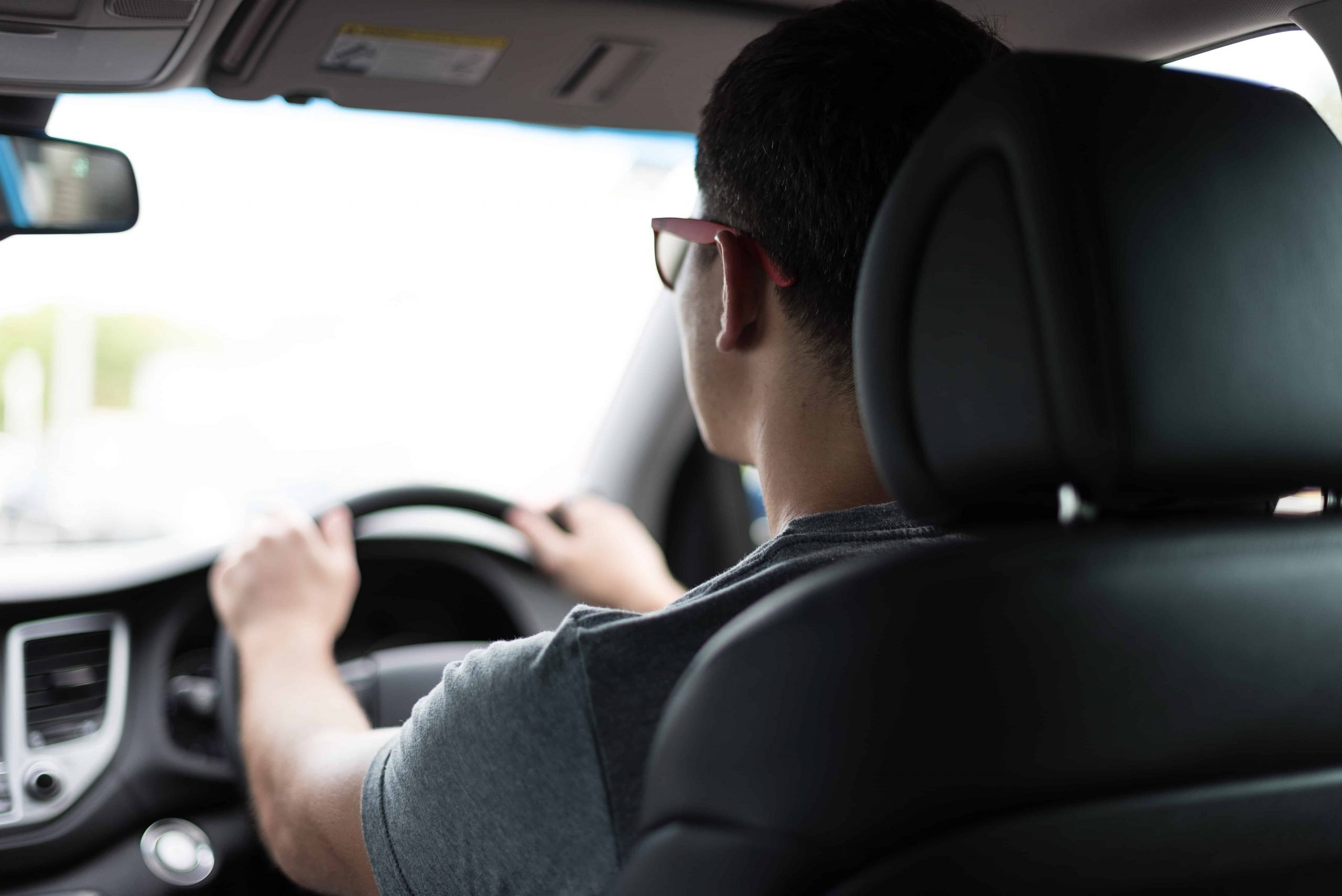 A man driving in his car wearing glasses.