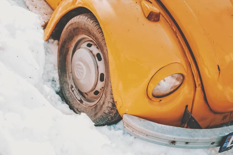 A yellow car is parked in the snow.