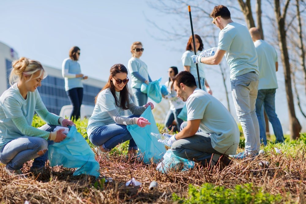 A group of people picking up trash in the grass.