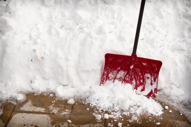 A red snow shovel is in the snow.