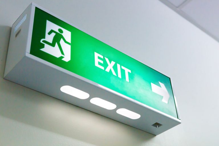 A green exit sign hanging from the ceiling.