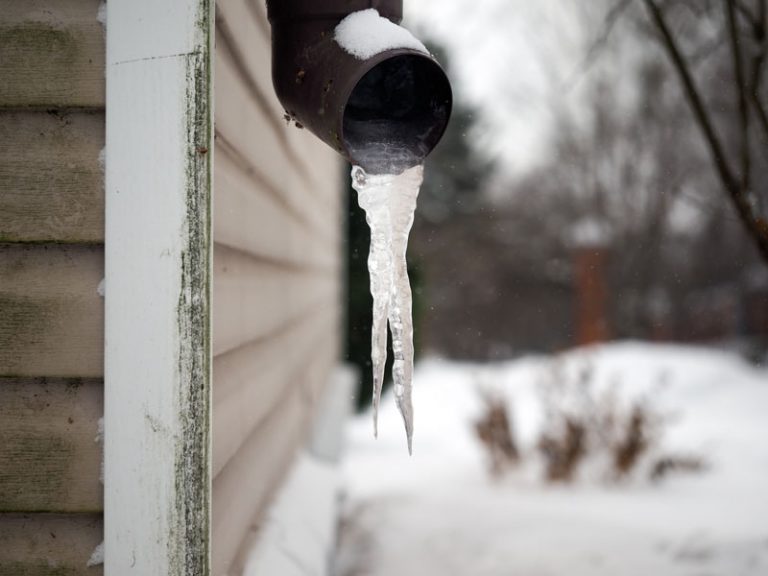 A pipe with icicles hanging from it's side.