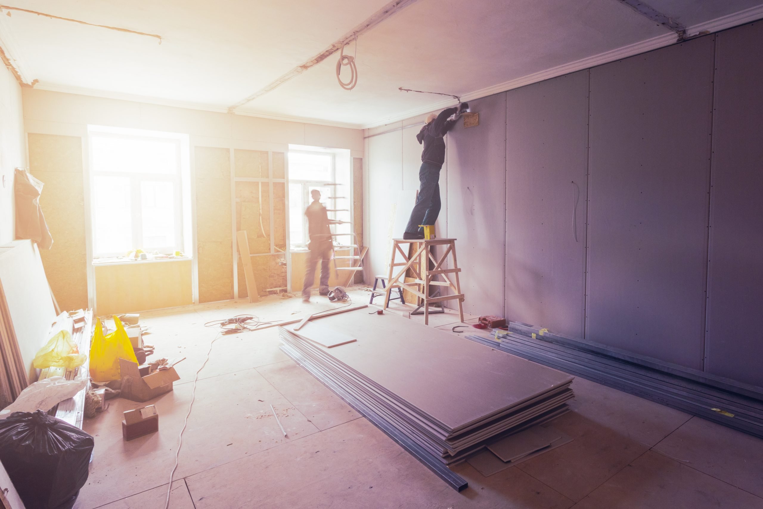 A man standing on top of a ladder in the middle of a room.