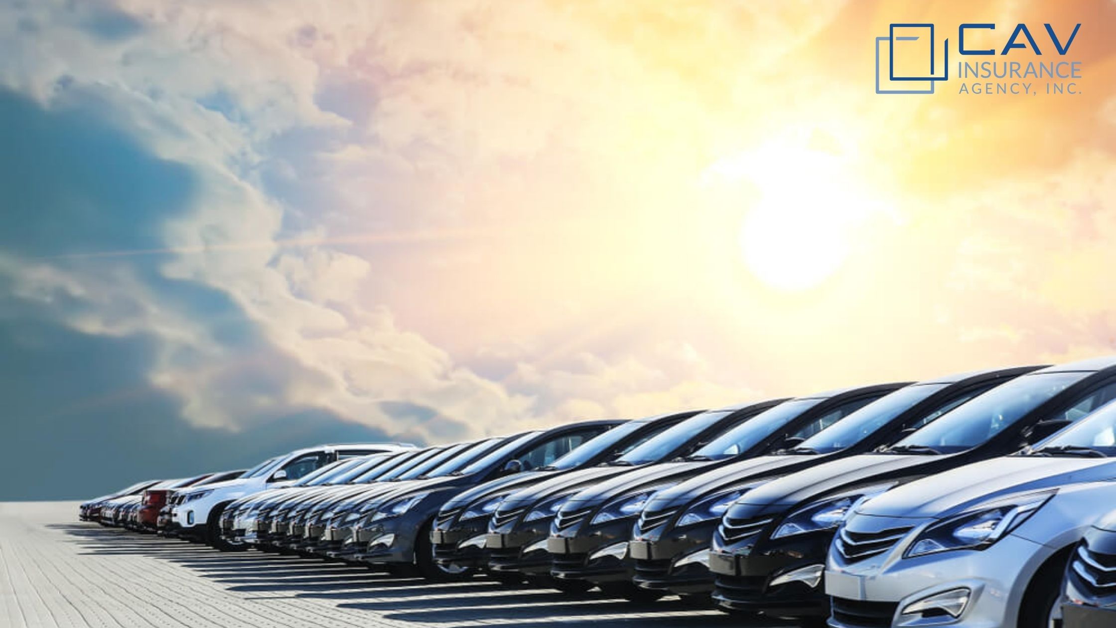 A row of parked cars sitting in front of the sun.