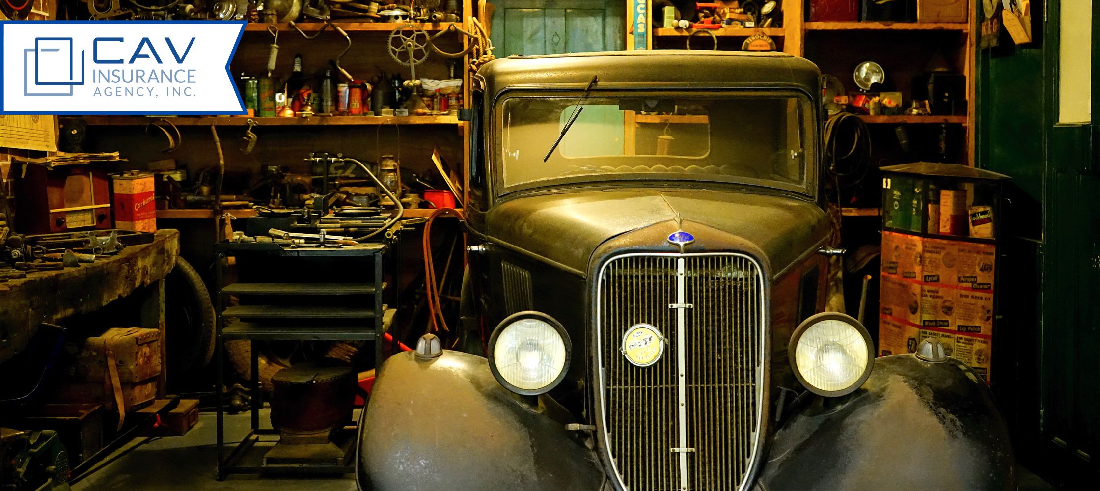 A car in the garage with many tools on the wall.