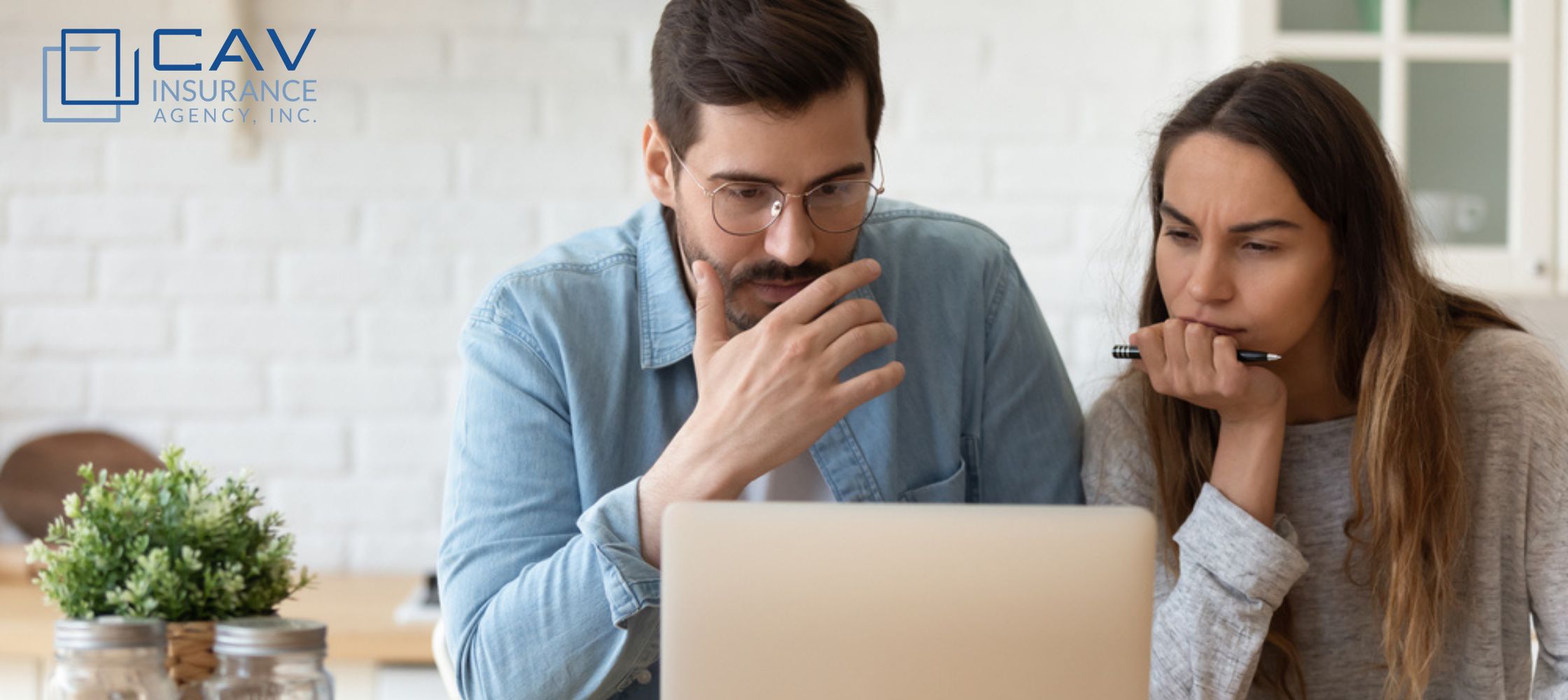 A man sitting at a table looking at his laptop.