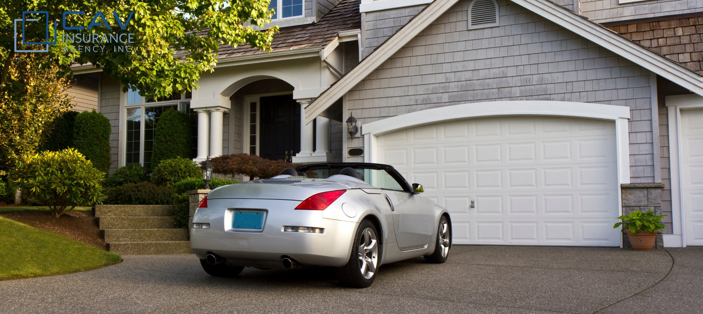 A silver car parked in front of a house.