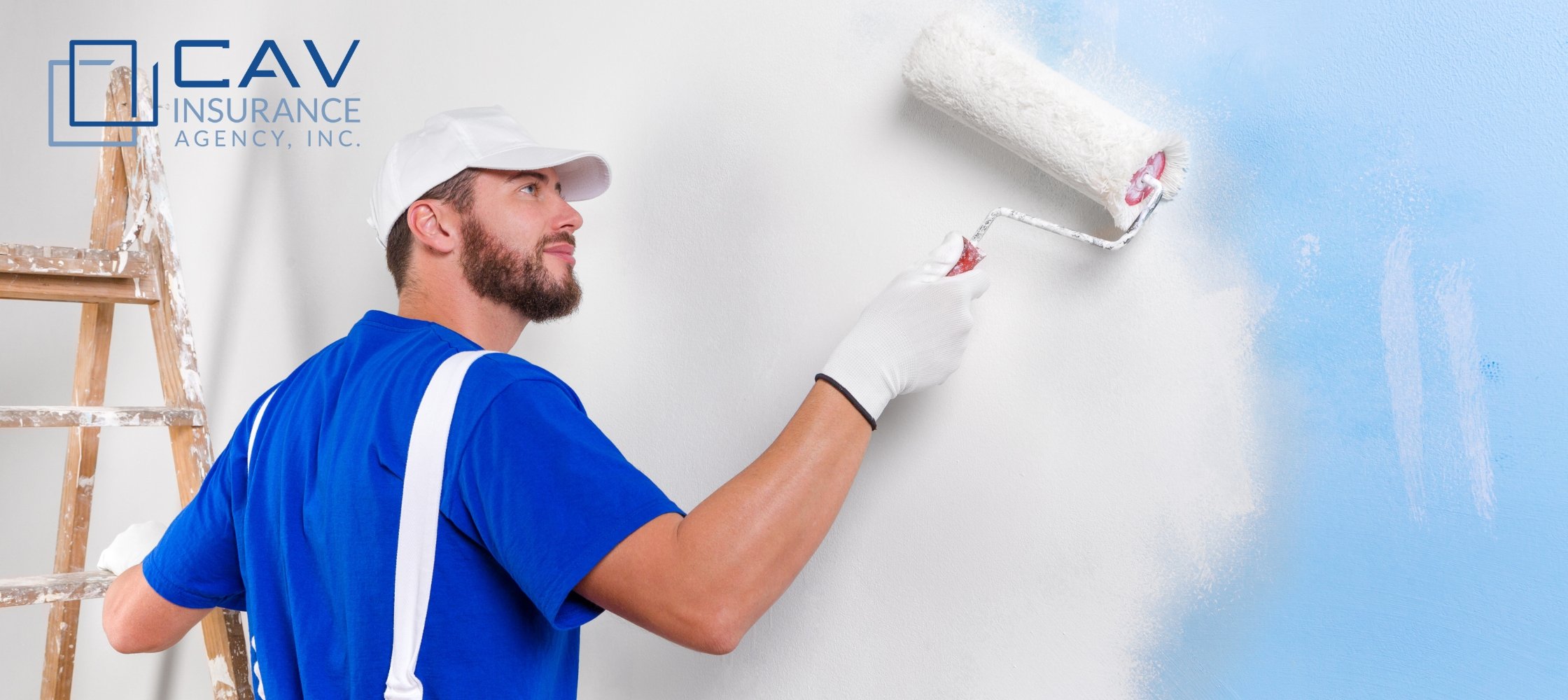 A man in blue shirt painting wall with white paint.