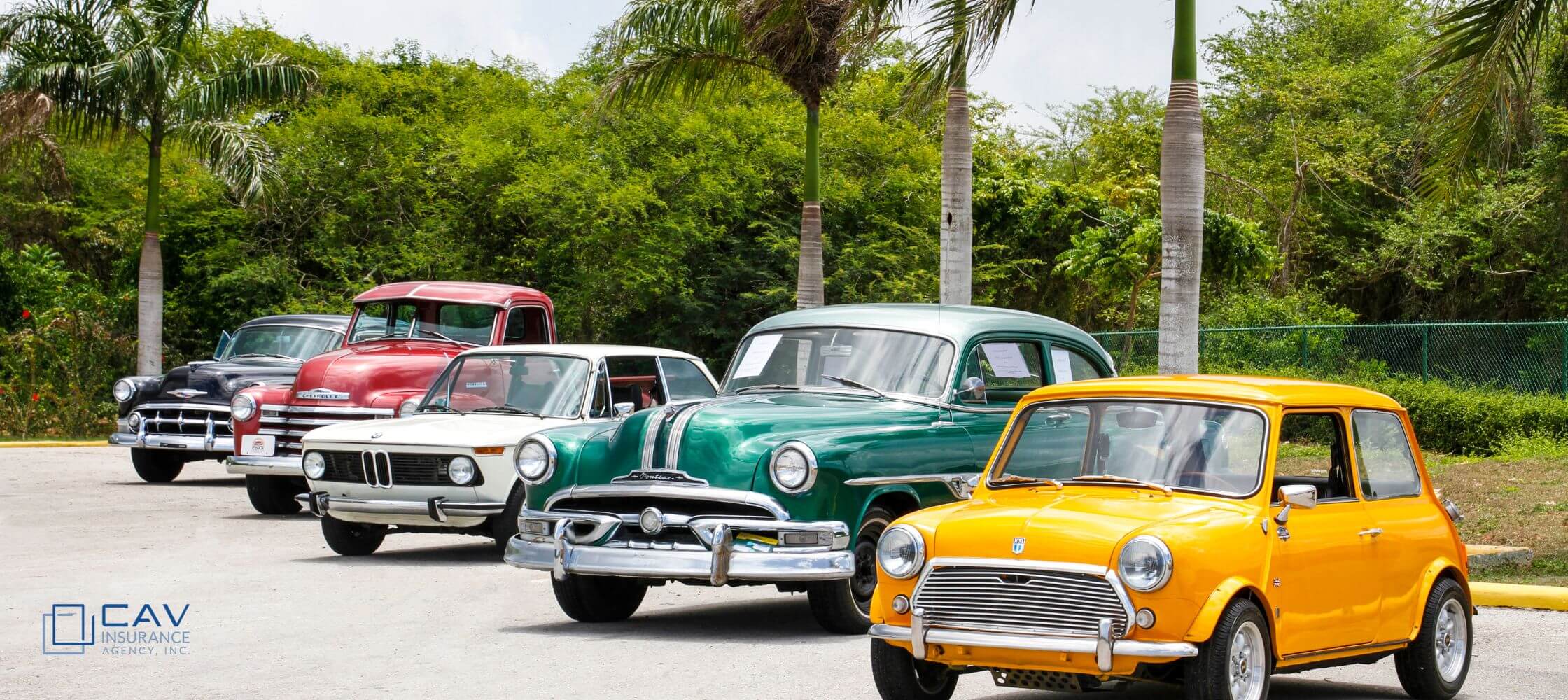 A group of old cars parked in the street.