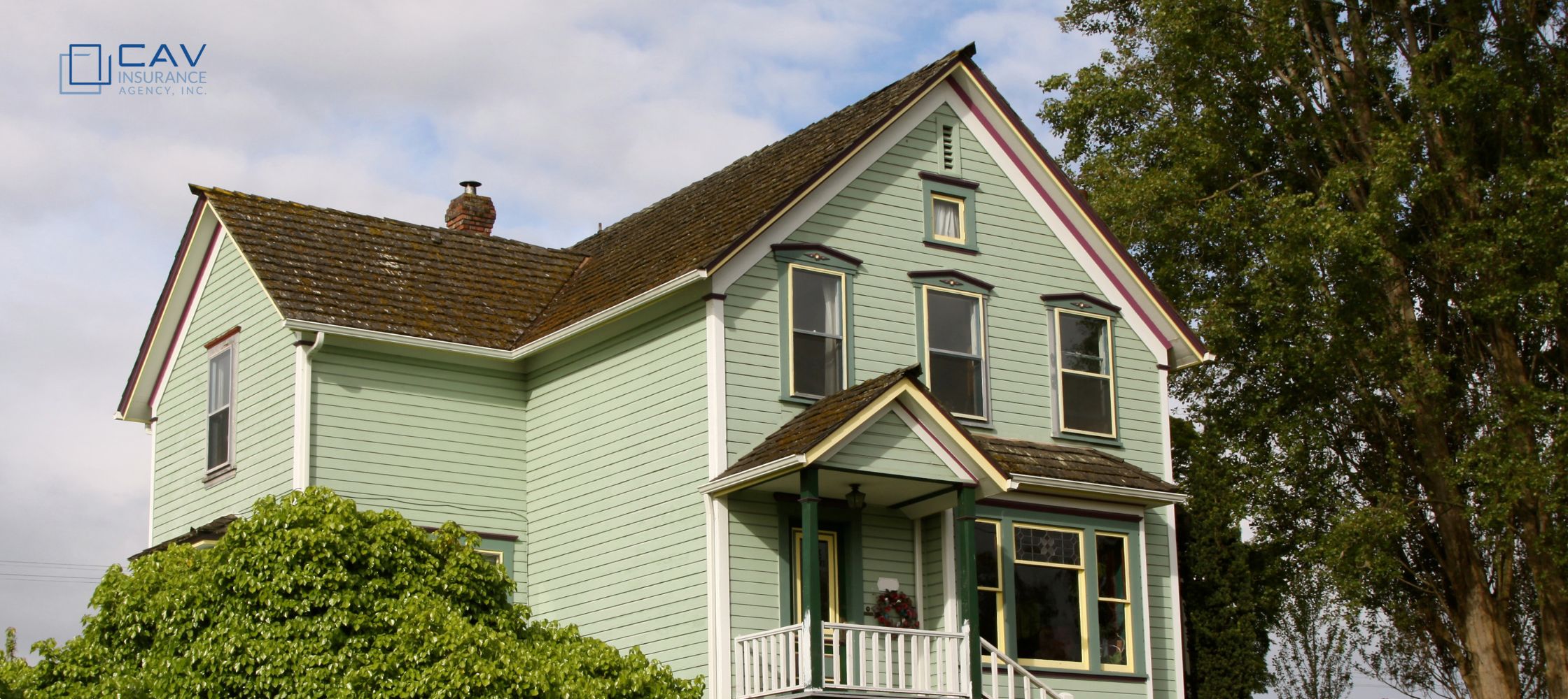 A green house with a brown roof and white trim.